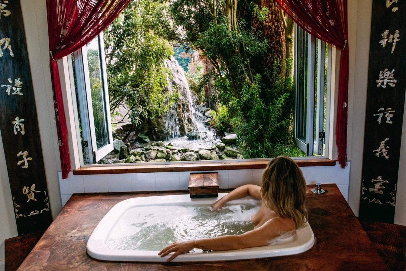 Person seated deeply immersed in an AQVA Haiku spa, daylight from the window